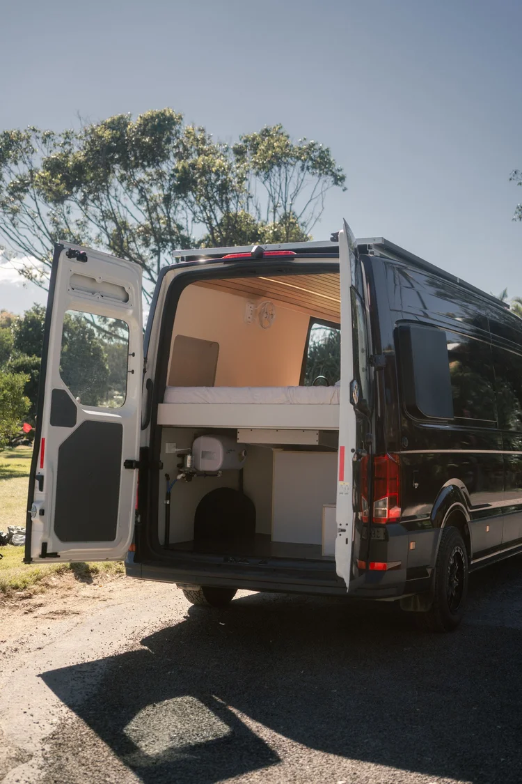 The deep-purple Bondi Van Co campervan parked on grass with its rear doors open